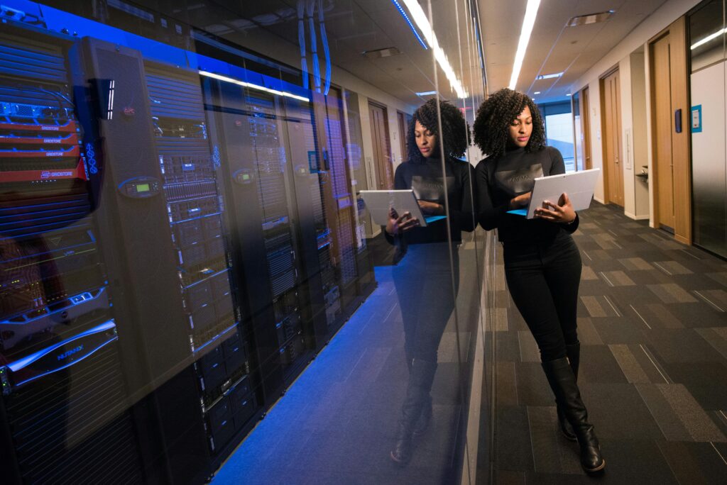 Mulher com tablet em corredor de data center, inspecionando servidores